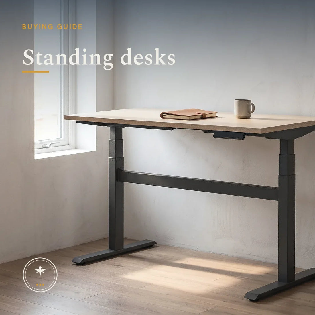 A plain sit-stand desk raised to standing height in a sparse room, its dark steel frame and legs visible beneath a pale wood top, with a notebook and mug in morning light from a window.